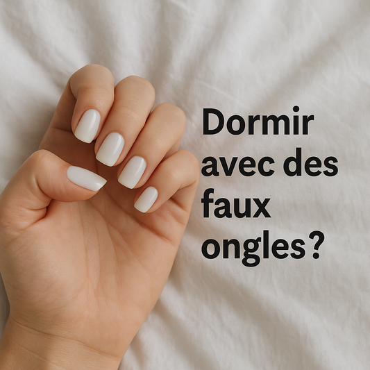 Main féminine avec faux ongles blancs posée sur un drap blanc, accompagnée du texte "Dormir avec des faux ongles ?" pour illustrer les précautions à prendre pendant le sommeil.