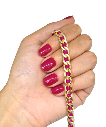Main avec faux ongles fuchsia courts et arrondis, finition brillante, tous les ongles visibles
