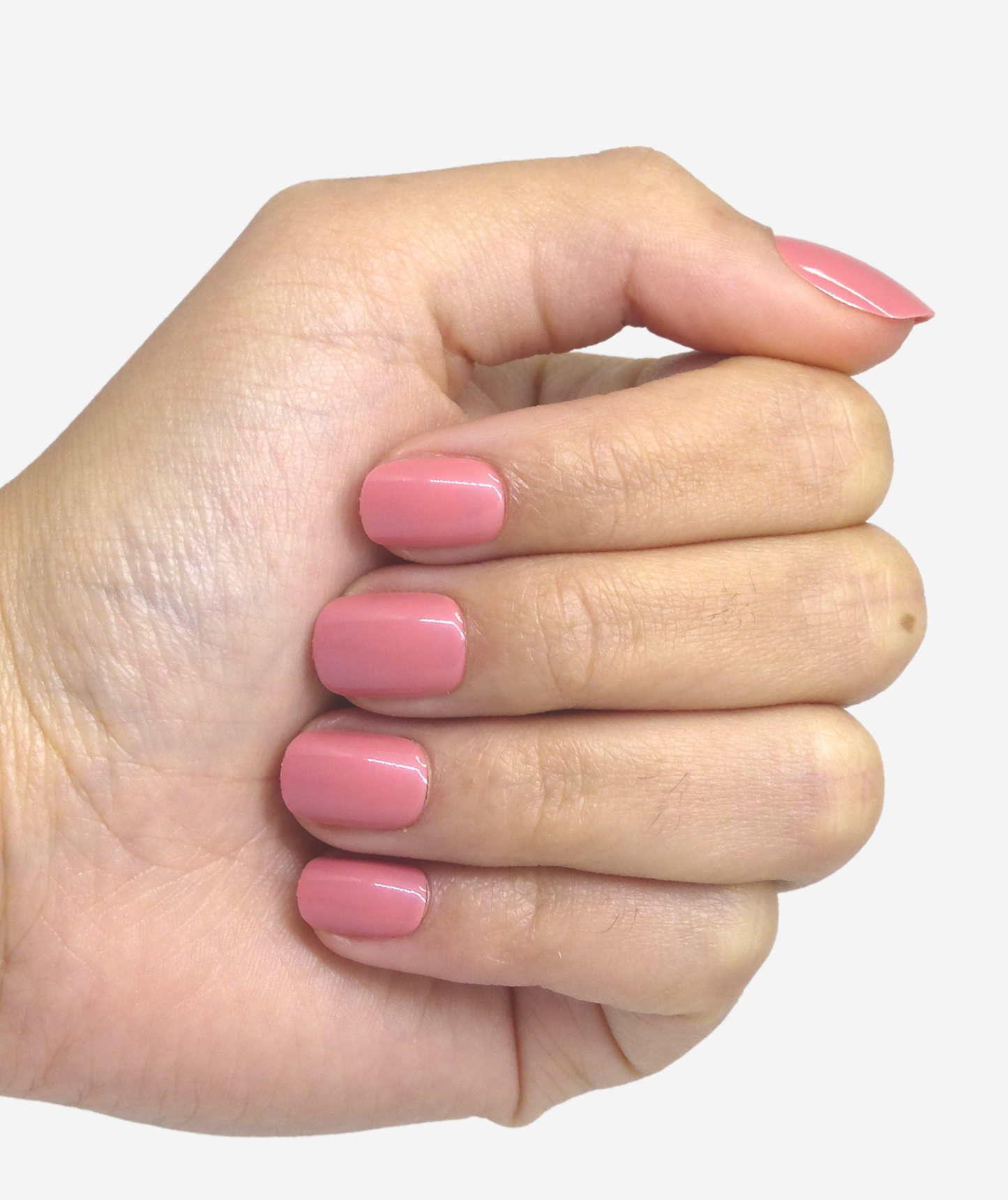 Main fermée avec des faux ongles rose pale sur les ongles