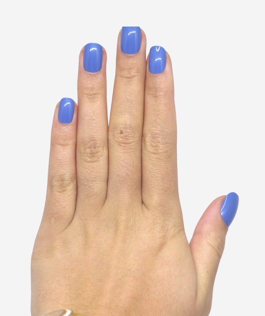Main portant faux ongles courts bleu clair brillants visibles sur poing fermé