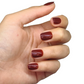 Faux ongles marron chaud posés sur main fermée, courts arrondis, brillance visible