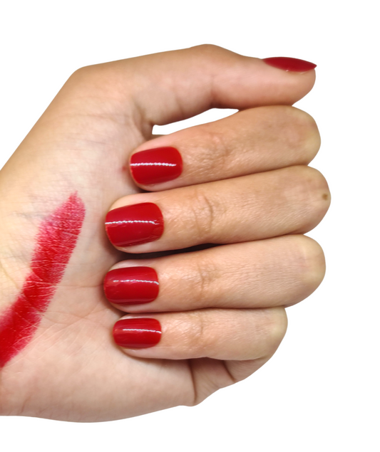 Faux ongles rouges foncés brillants portés sur une main fermée, format court arrondi