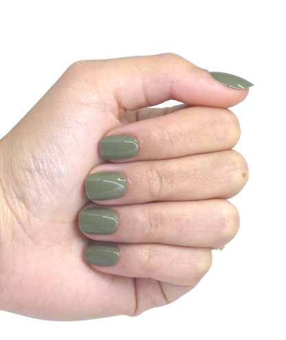 Main portant faux ongles courts vert kaki brillants, 5 doigts visibles